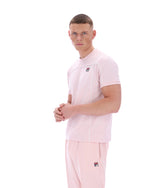Man wearing a pink t-shirt with a FILA logo on the chest and matching trousers on a white background