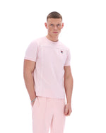 Man wearing a pink t-shirt with a FILA logo on the chest and matching trousers on a white background