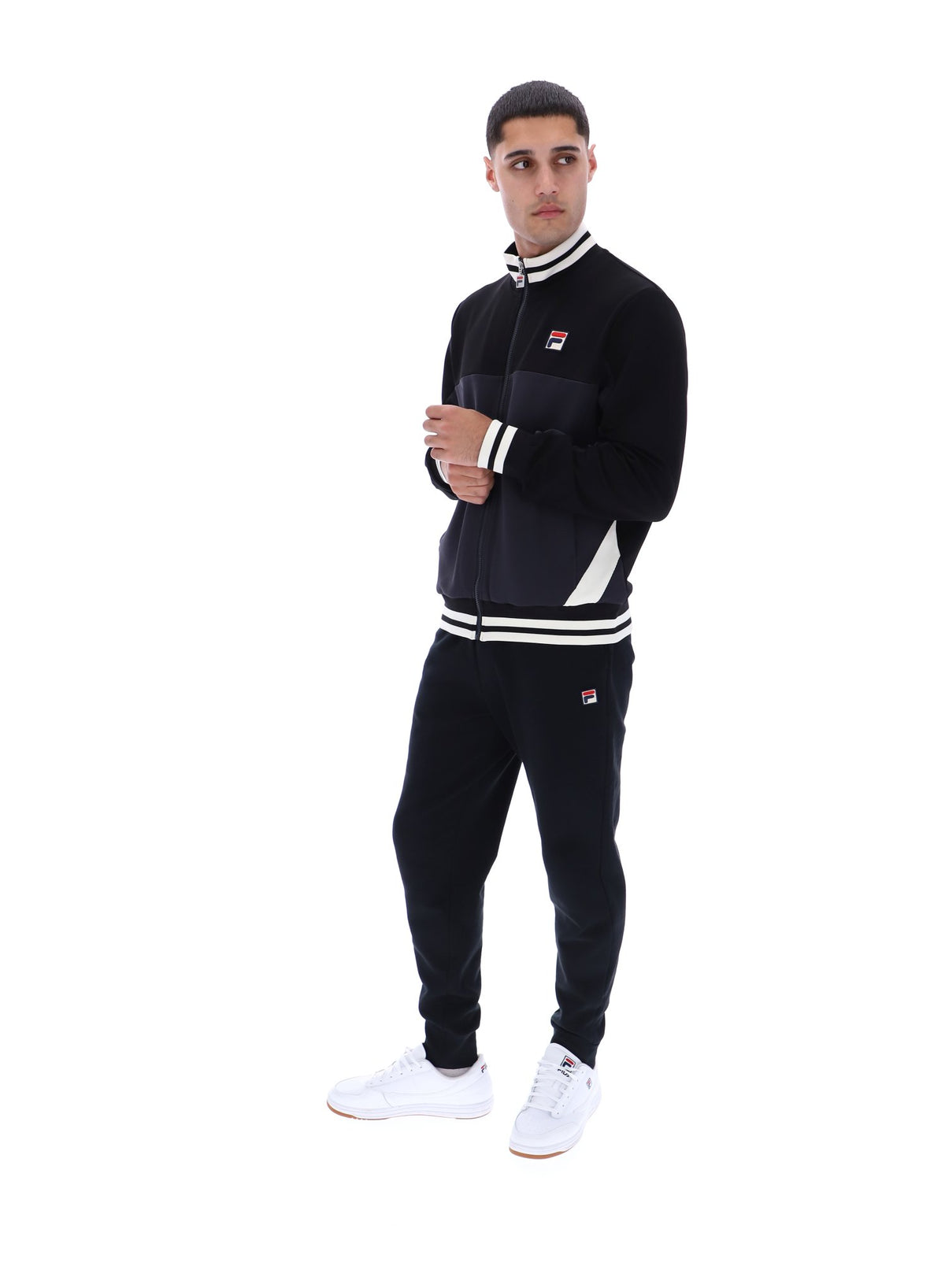 Person wearing a black tracksuit with white accents and FILA logo on a white background
