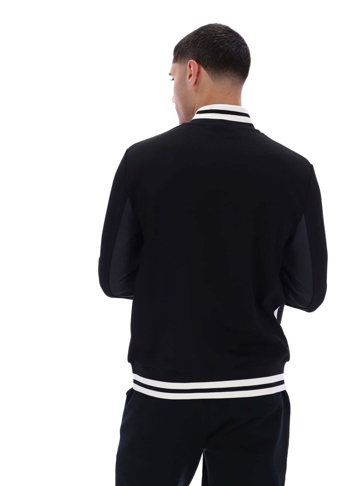Man wearing a black tracksuit with white stripes on a white background