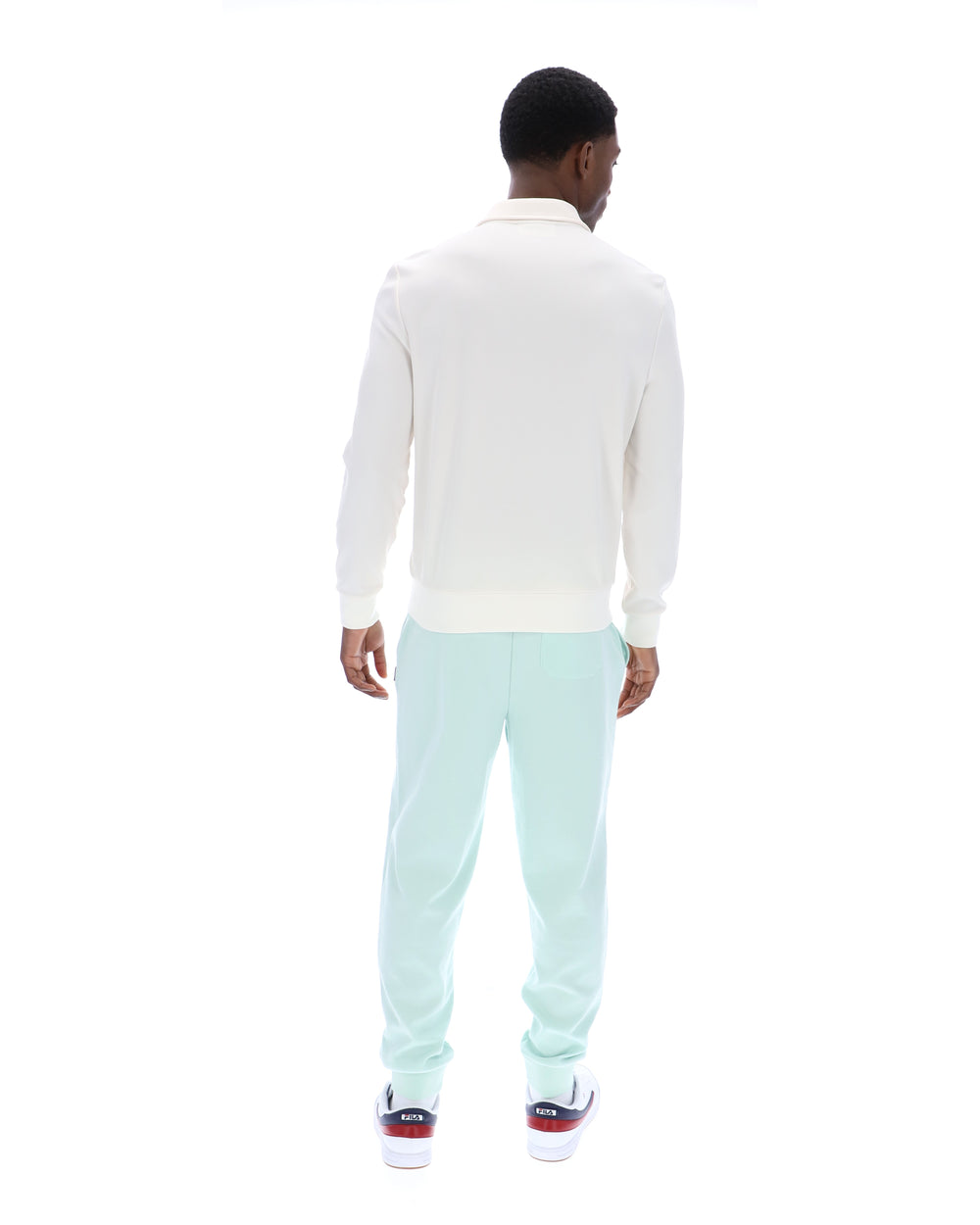 Man wearing a white sweater and light blue pants on a white background