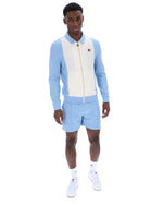 Man wearing a light blue and white outfit with a brand logo on a white background