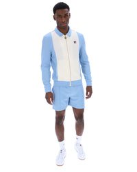 Man wearing a light blue and white outfit with a brand logo on a white background