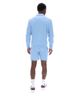 Man wearing a light blue outfit with shorts on a white background