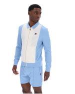 Man wearing a light blue and white tracksuit with a visible brand logo on a white background
