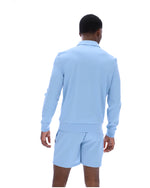 Person wearing a light blue long-sleeve shirt and shorts set on a white background