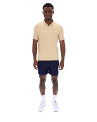 Man wearing a beige polo shirt and navy shorts on a white background