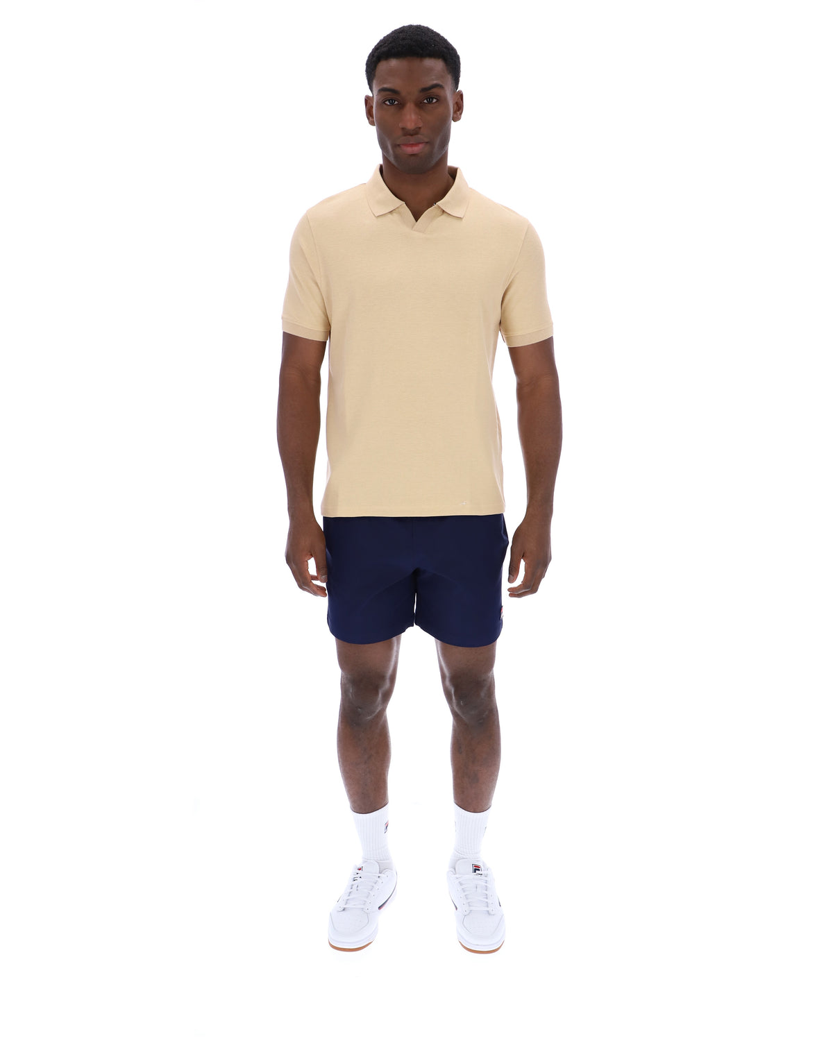 Man wearing a beige polo shirt and navy shorts on a white background