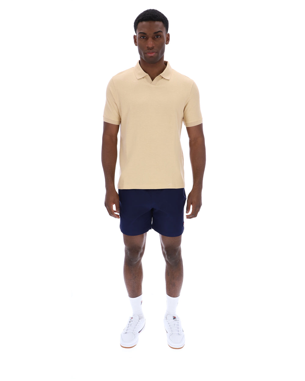 Man wearing a beige polo shirt and navy shorts on a white background