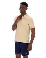 Man wearing a beige polo shirt and navy shorts on a white background