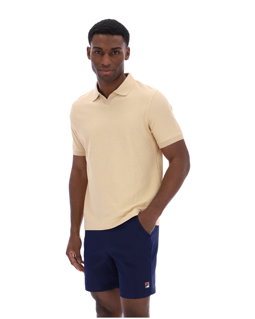 Man wearing a beige polo shirt and navy shorts on a white background
