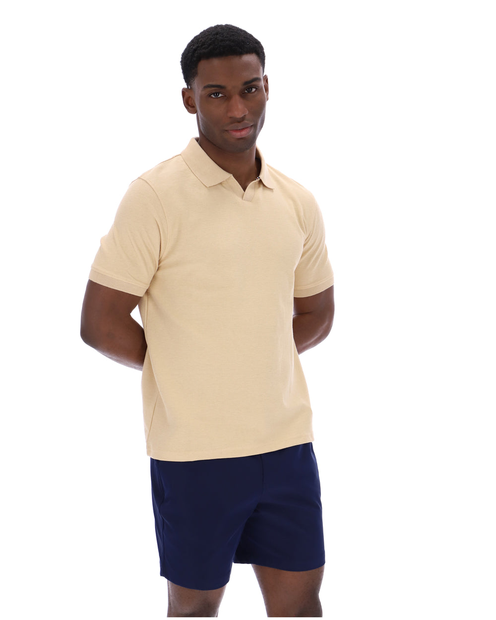 Man wearing a beige polo shirt and navy shorts on a white background