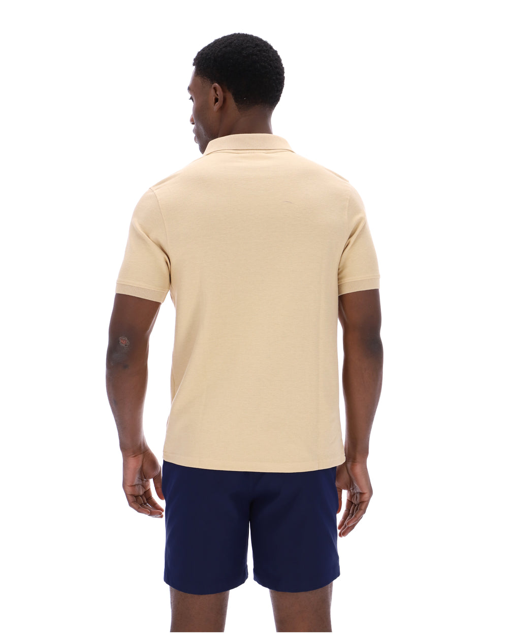 Man wearing a beige polo shirt and navy shorts on a white background
