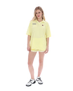 Woman wearing a yellow tennis outfit with a logo on a white background