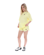 Woman wearing a yellow tennis outfit with a visible brand logo on a white background