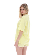 Woman wearing a yellow textured top and shorts on a white background