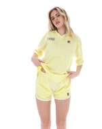 Woman wearing a yellow sports outfit with visible branding on a white background