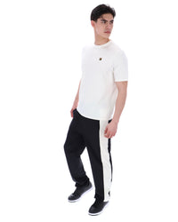 Man wearing a white t-shirt with a small FILA gold logo, paired with black pants, against a white background