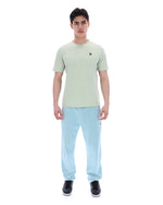 Person wearing a light green t-shirt with a FILA logo and light blue pants on a white background