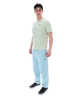 Person wearing a light green t-shirt with a FILA logo and light blue pants on a white background