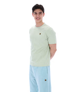 Person wearing a light green t-shirt and light blue pants on a white background