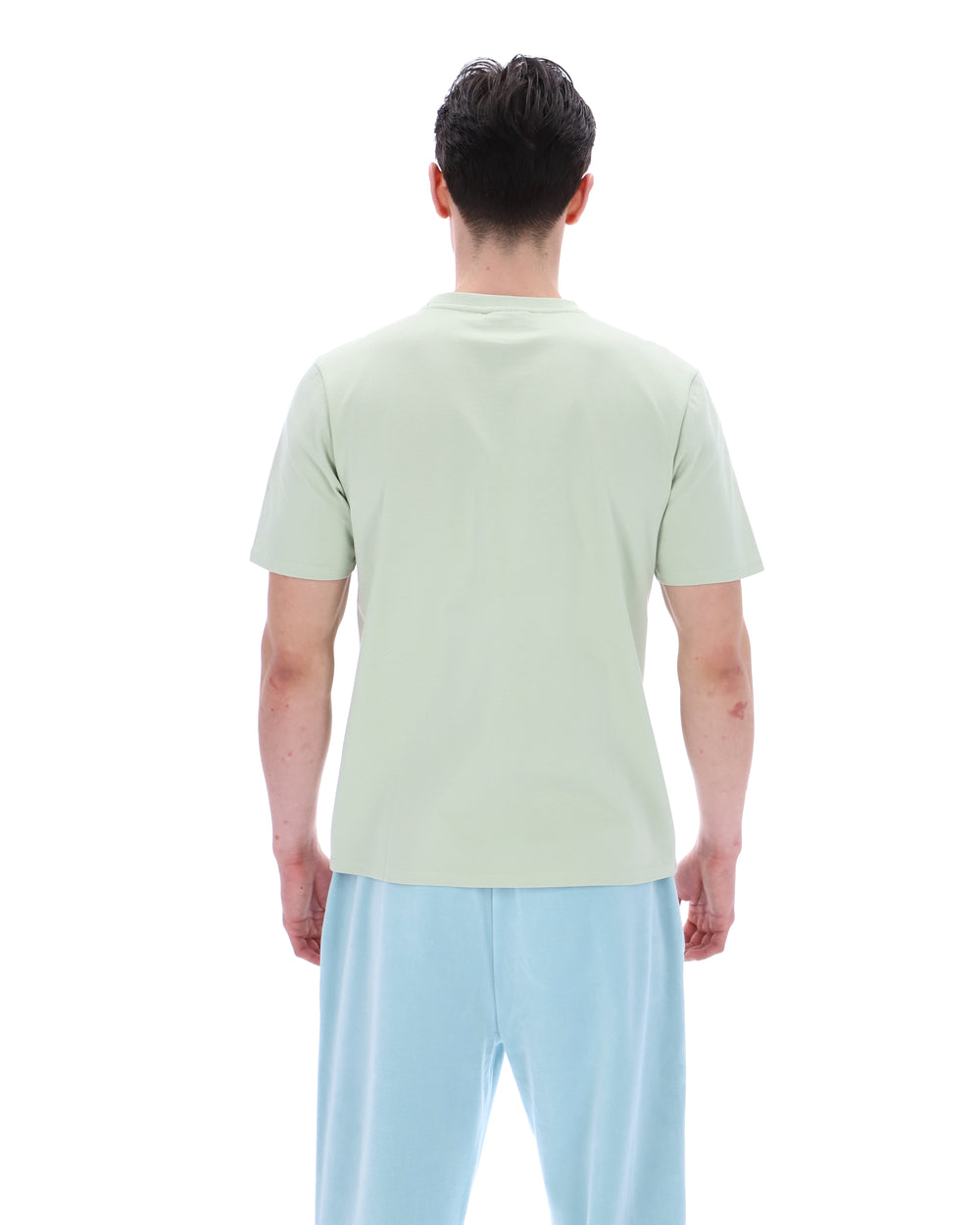 Person wearing a light green t-shirt and light blue pants on a white background
