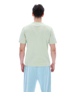 Person wearing a light green t-shirt and light blue pants on a white background