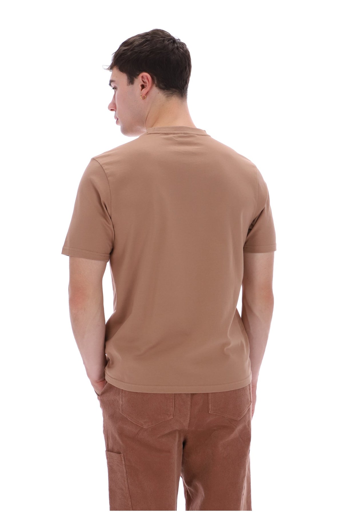 A man shown from the back wearing a short-sleeve crewneck t-shirt in a warm tan shade and brown pants, set against a plain white background.