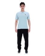 Man wearing a light blue t-shirt and black pants on a white background