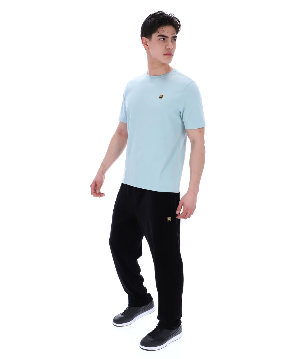 Man wearing a light blue t-shirt and black pants on a white background