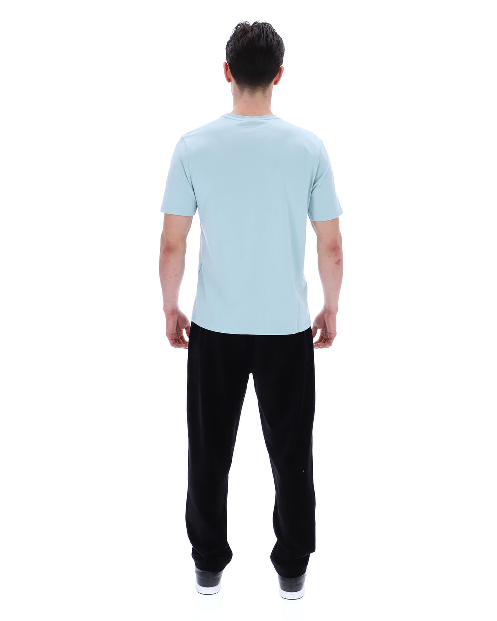 Man wearing a light blue t-shirt and black pants on a white background