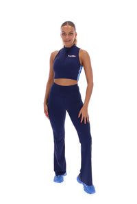 A woman wearing a navy blue zip-up crop top with seamless look and FILA x TALA logo branded on the front.