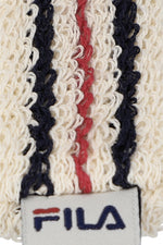 A close-up of a beige retro headband with a red and blue stripe pattern and the FILA logo embroidered on it.