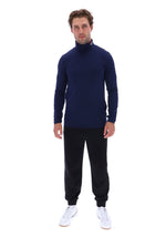 A man modeling a navy blue long-sleeve mock neck turtleneck sweater, paired with black joggers and white sneakers, against a solid white background.