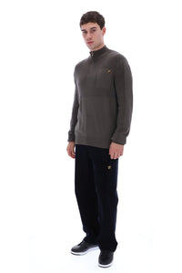 A man modeling a dark brown quarter-zip fleece pullover with a small embroidered logo on the left chest, paired with black sweatpants and black sneakers, against a solid white background.