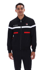 A man wearing a black Fila track jacket with white and red stripes, paired with matching black track pants, photographed against a solid white background.