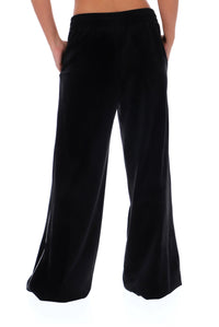 Black wide-leg velvet pants shown on a model from the back, featuring an elastic waistband and side pockets, set against a plain white background.