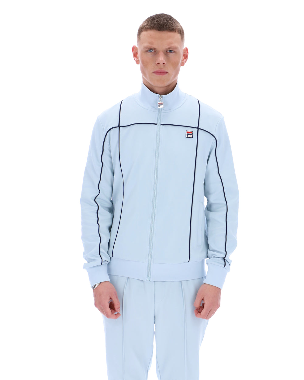 Man wearing a light blue tracksuit with a brand logo on a white background