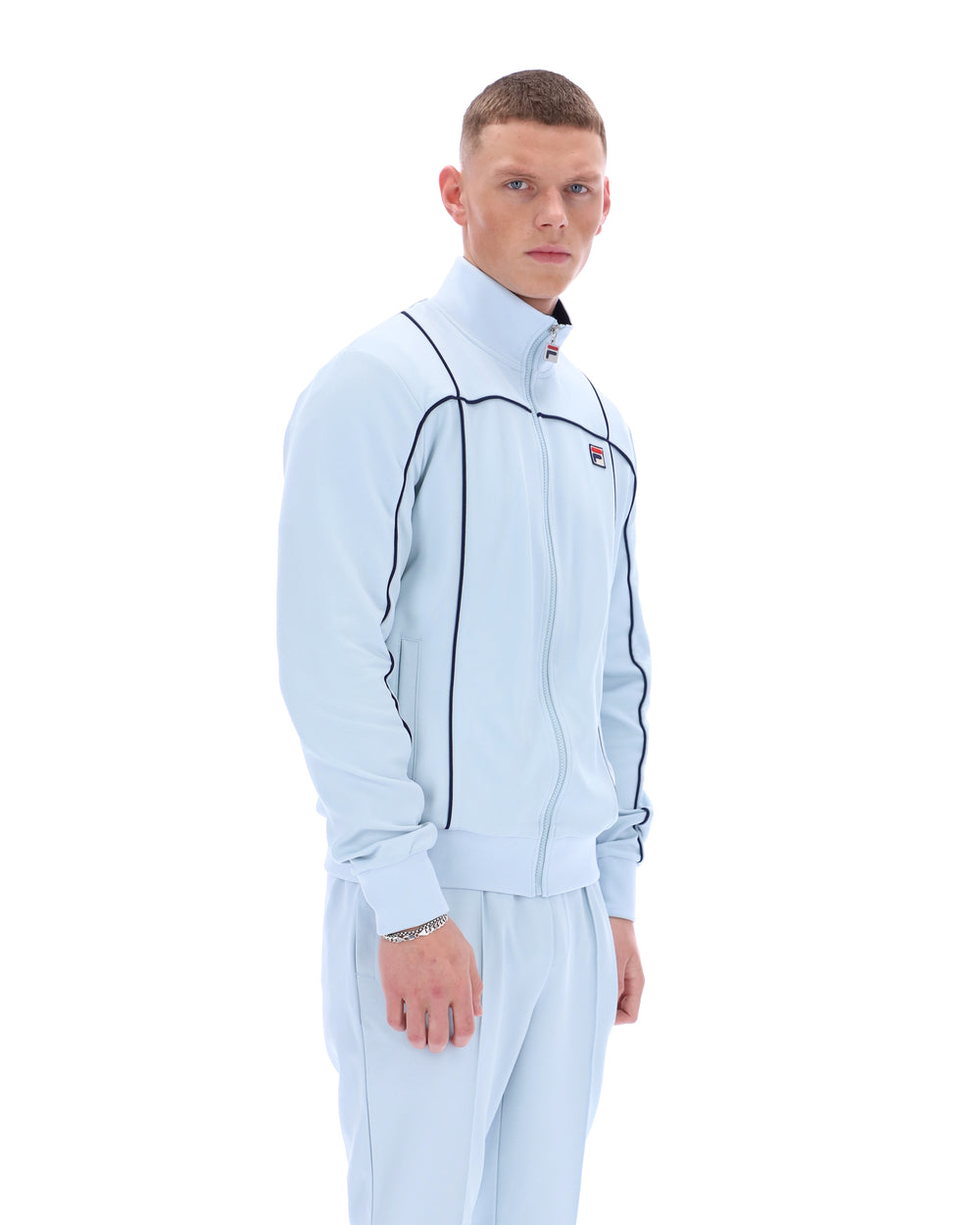 Man wearing a light blue tracksuit with a logo on a white background