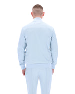 Man wearing a light blue sweater and pants on a white background