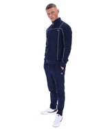 Man wearing a navy tracksuit with a logo on a white background