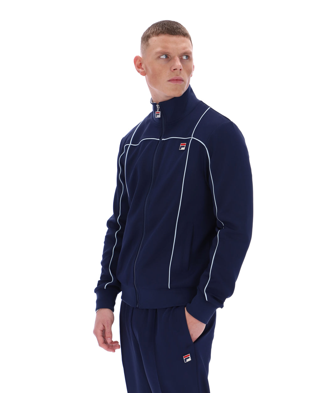 Man wearing a navy tracksuit with white piping on a white background