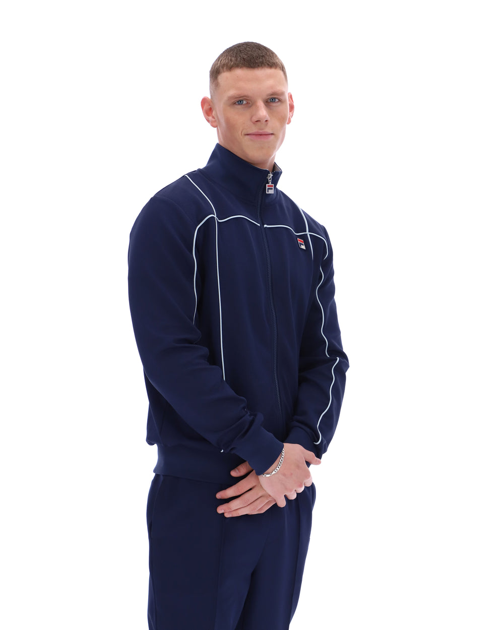 Man wearing a navy tracksuit with white piping on a white background