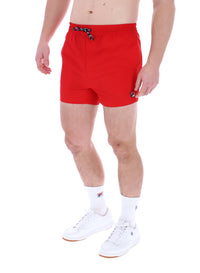A man wearing red Artoni Swim Shorts by FILA, featuring a drawstring waistband and side pockets.