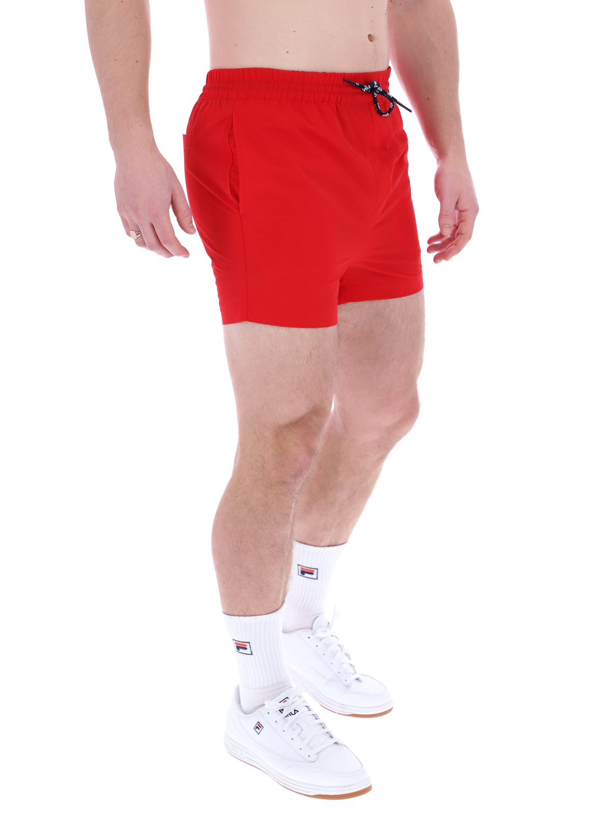 A man wearing red Artoni Swim Shorts by FILA, featuring a drawstring waistband and side pockets.