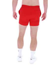 A man wearing red Artoni Swim Shorts by FILA, featuring a drawstring waistband and a back pocket.