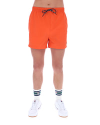 Person wearing bright orange shorts on a white background