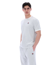 Person wearing a dawn blue t-shirt and pants with a brand logo on a white background
