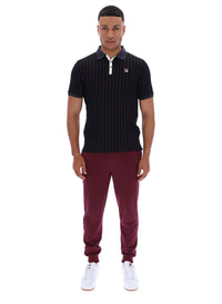 Man wearing a dark pinstripe polo shirt and maroon pants with a FILA logo on both, on a white background