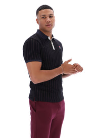 Man wearing a dark pinstripe polo shirt and maroon pants with a FILA logo on both, on a white background